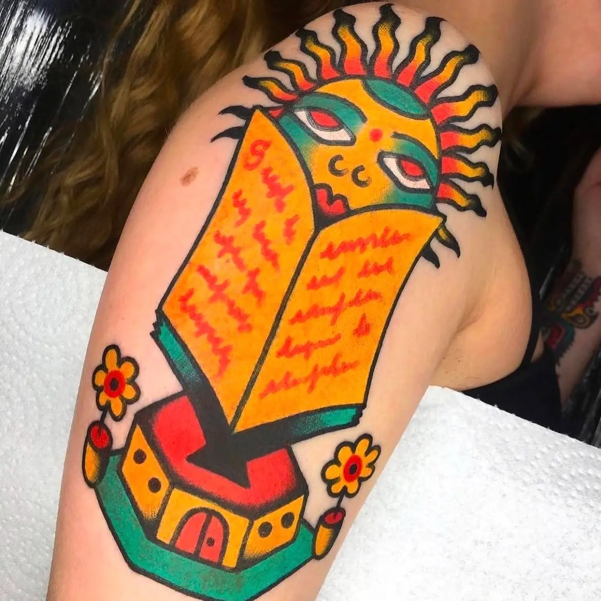 Tatuaje colorido de sol y libro